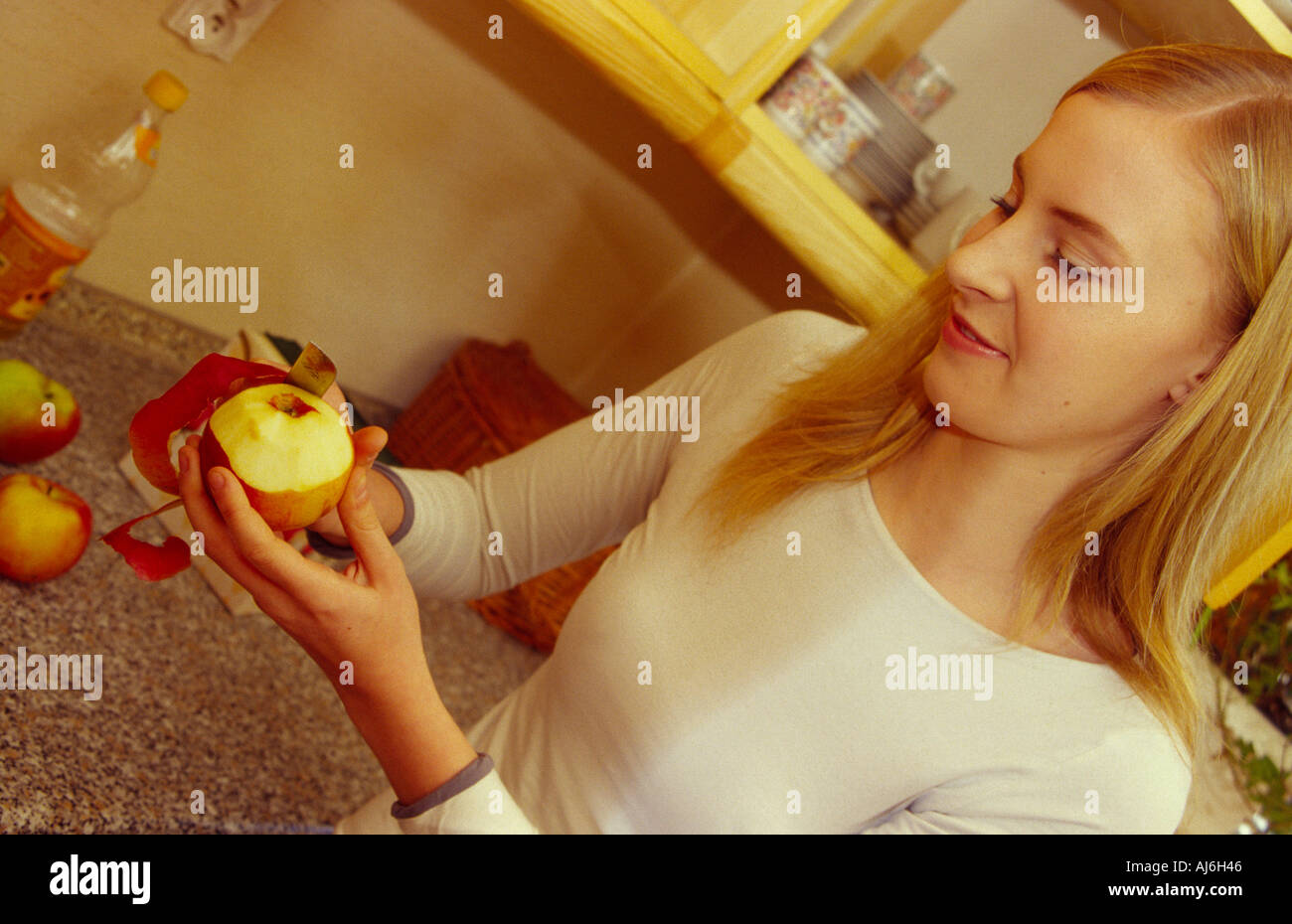 Young woman peeling une pomme dans la cuisine. Banque D'Images