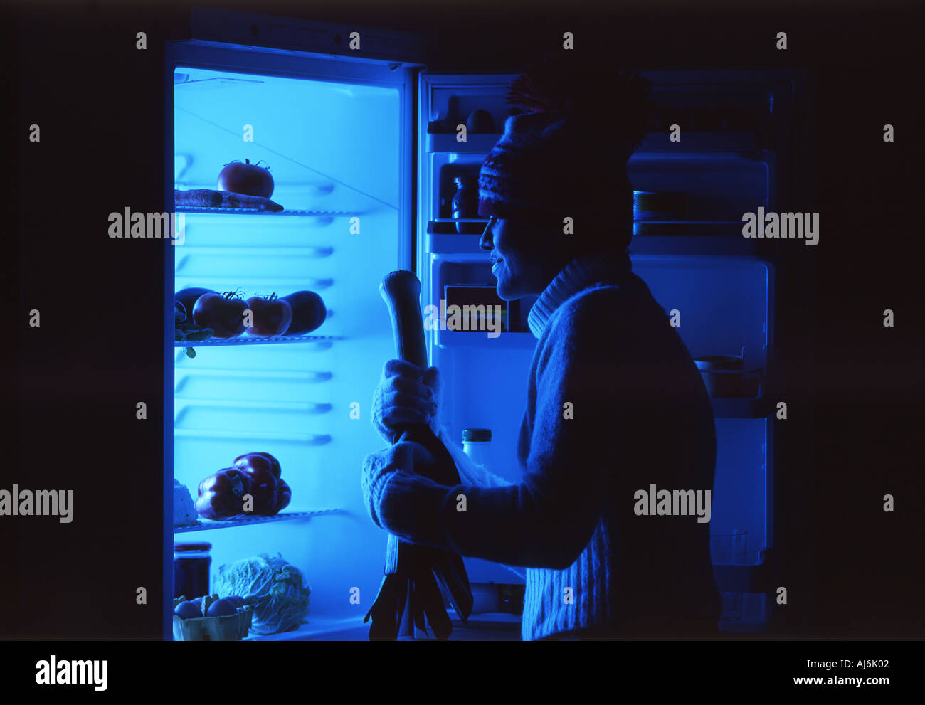 Jeune femme à la recherche dans le réfrigérateur pendant la nuit. Banque D'Images