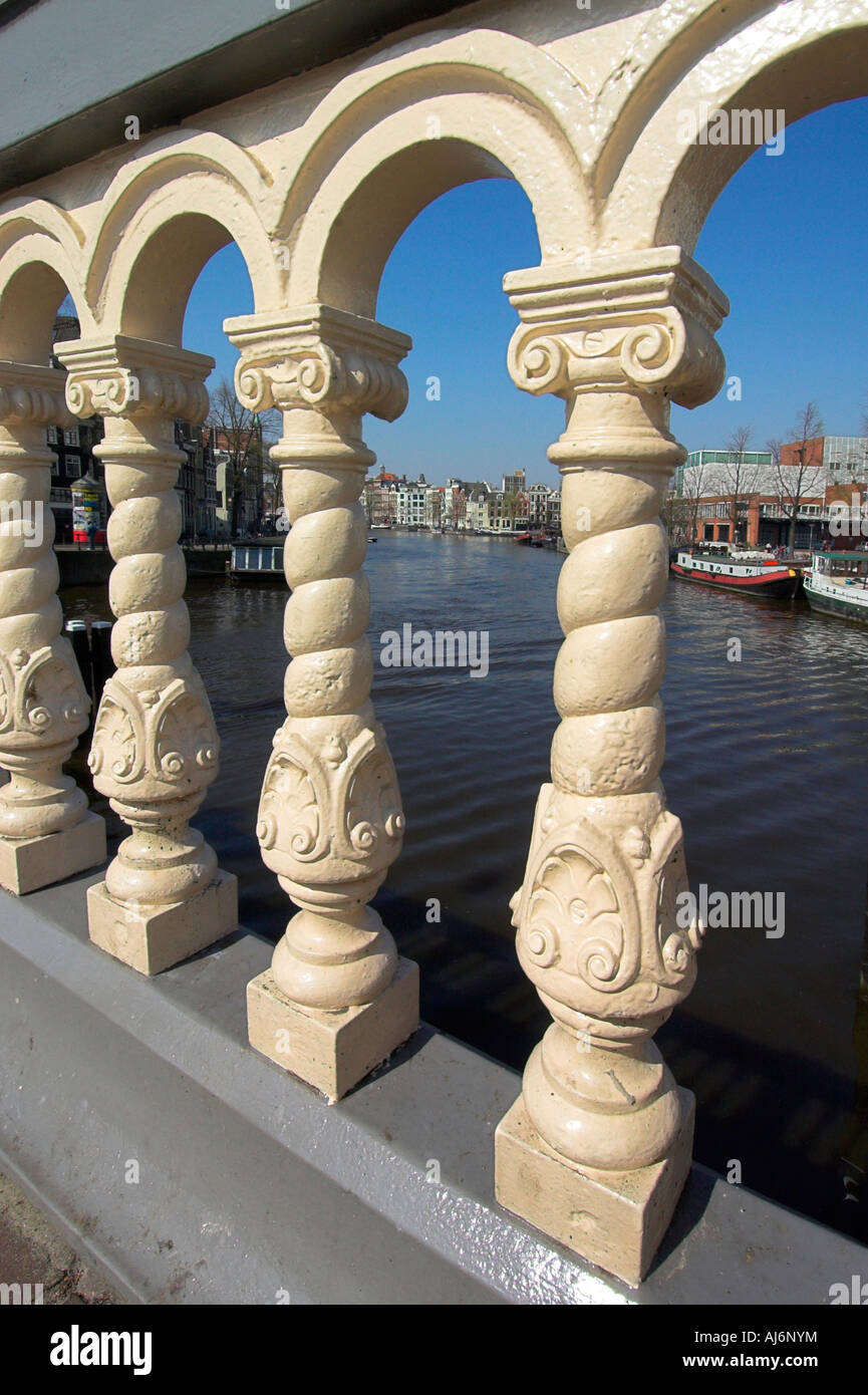 Une vue le long de la rivière Amstel à Amsterdam vu à travers les barreaux de la Blauwe Brug bridge Banque D'Images