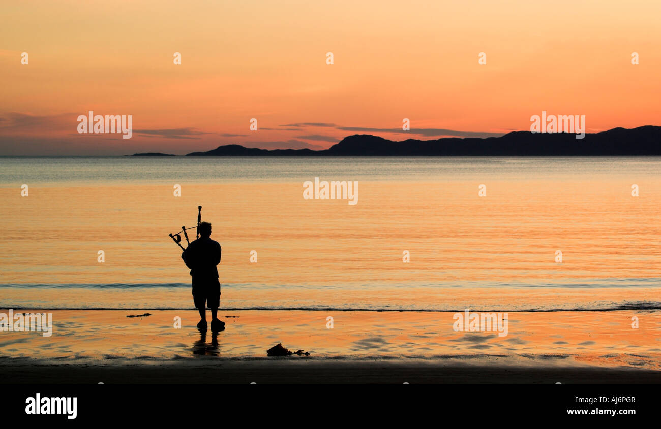 Un joueur de cornemuse silhouette sur le coucher du soleil sur la plage d'Arisaig dans les highlands avec Skye au-delà Banque D'Images