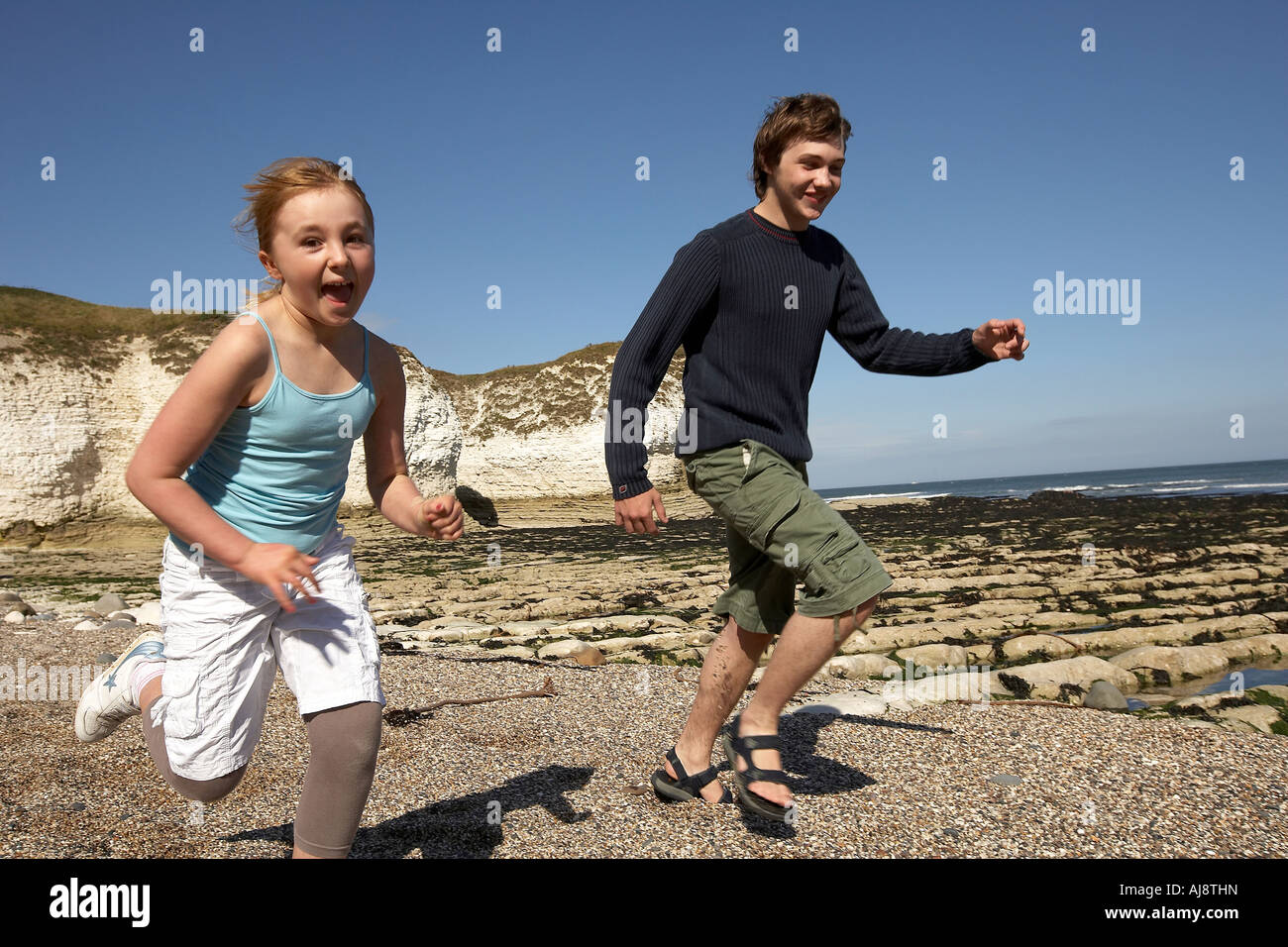 Neuf ans, fille et garçon de quinze ans d'exécution sur beach Flamborough Head beach East Yorkshire UK Banque D'Images