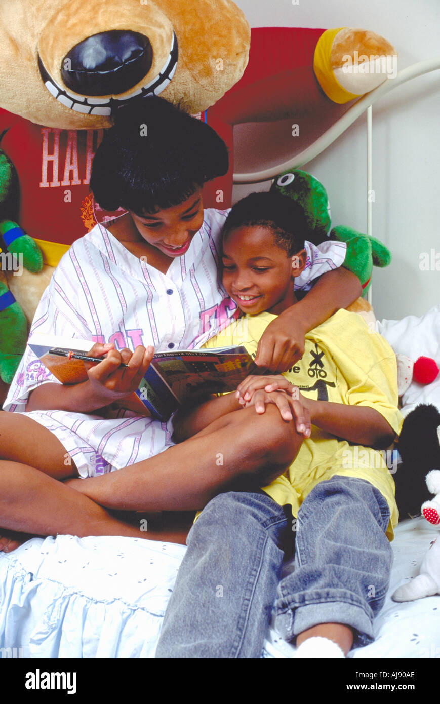 African American l'âge de 13 et 9 ans, soeur et frère fait ses devoirs dans le lit. St Paul Minnesota USA Banque D'Images