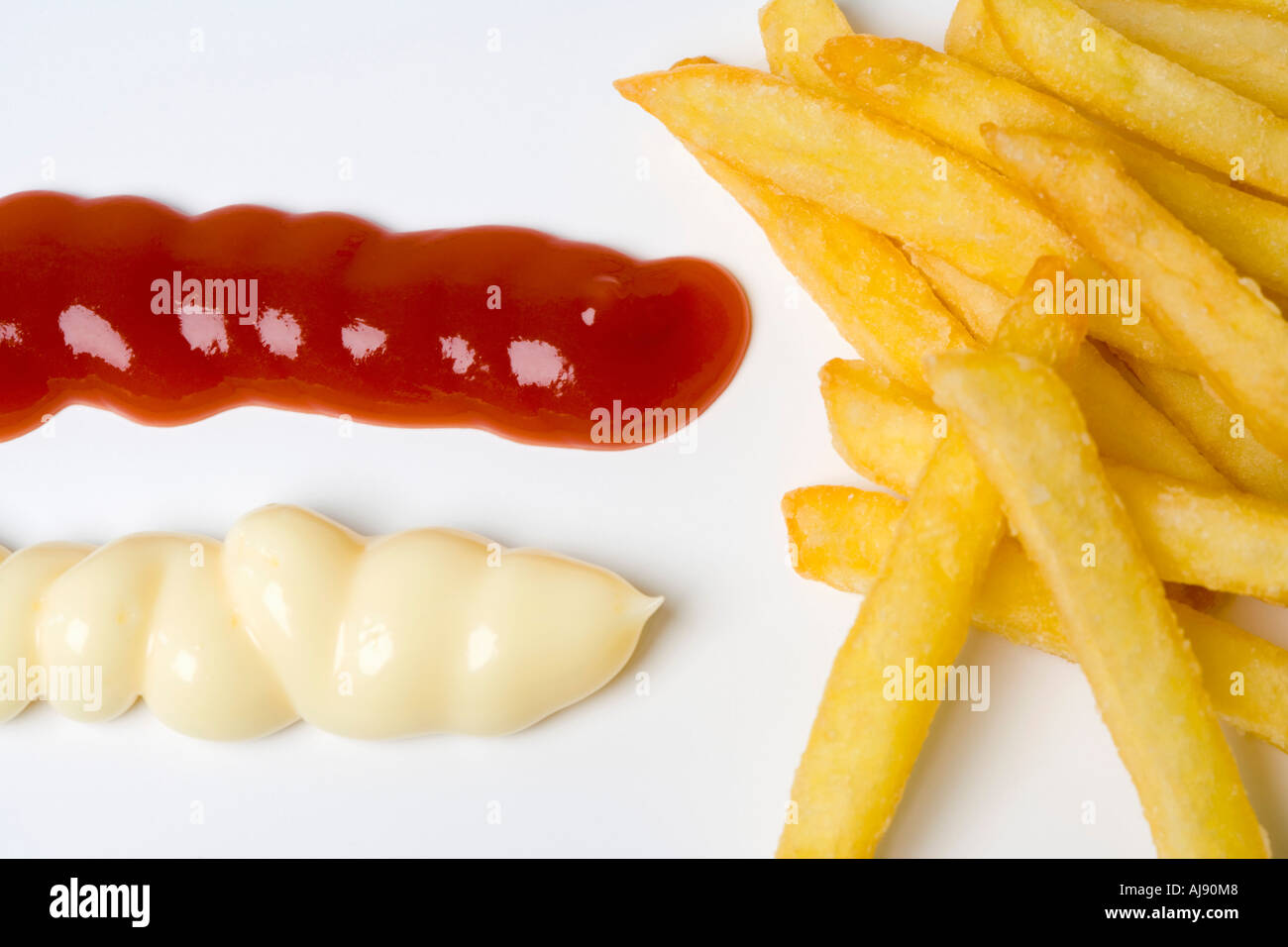 Tas de frites à côté de blobs de ketchup et de mayonnaise Banque D'Images