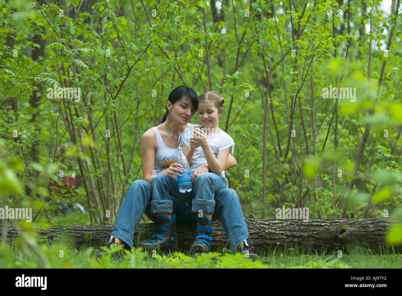 La mère et la fille assis sur un journal ensemble dans une forêt Banque D'Images