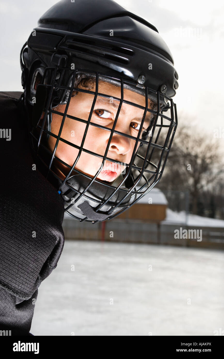 Garçon, joueur de hockey sur glace en uniforme et casque cage faisant face  moyenne Photo Stock - Alamy