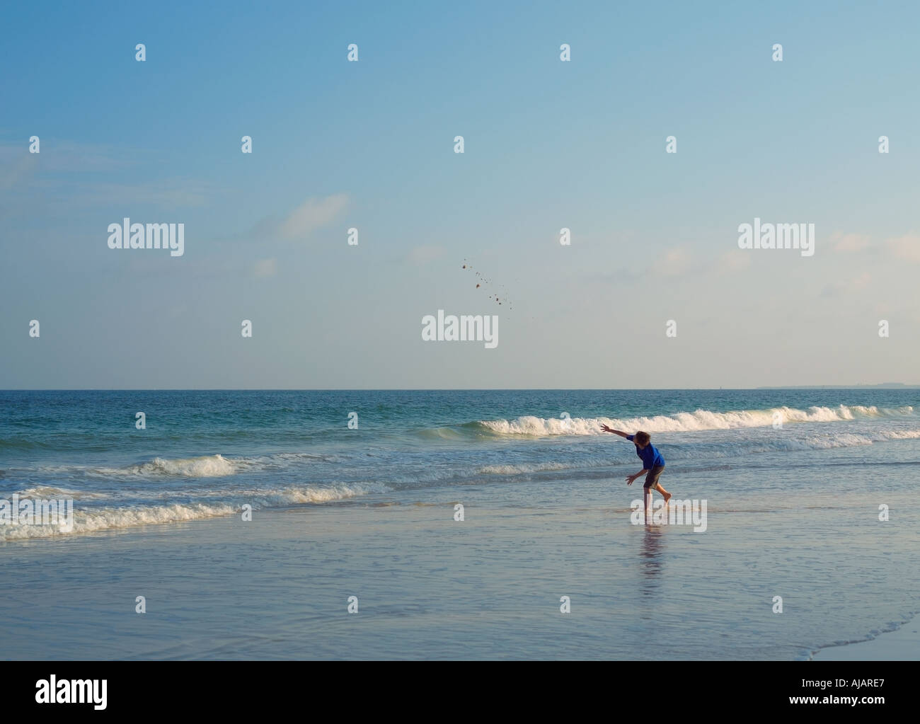 Boy on beach jeter du sable dans la mer. Banque D'Images