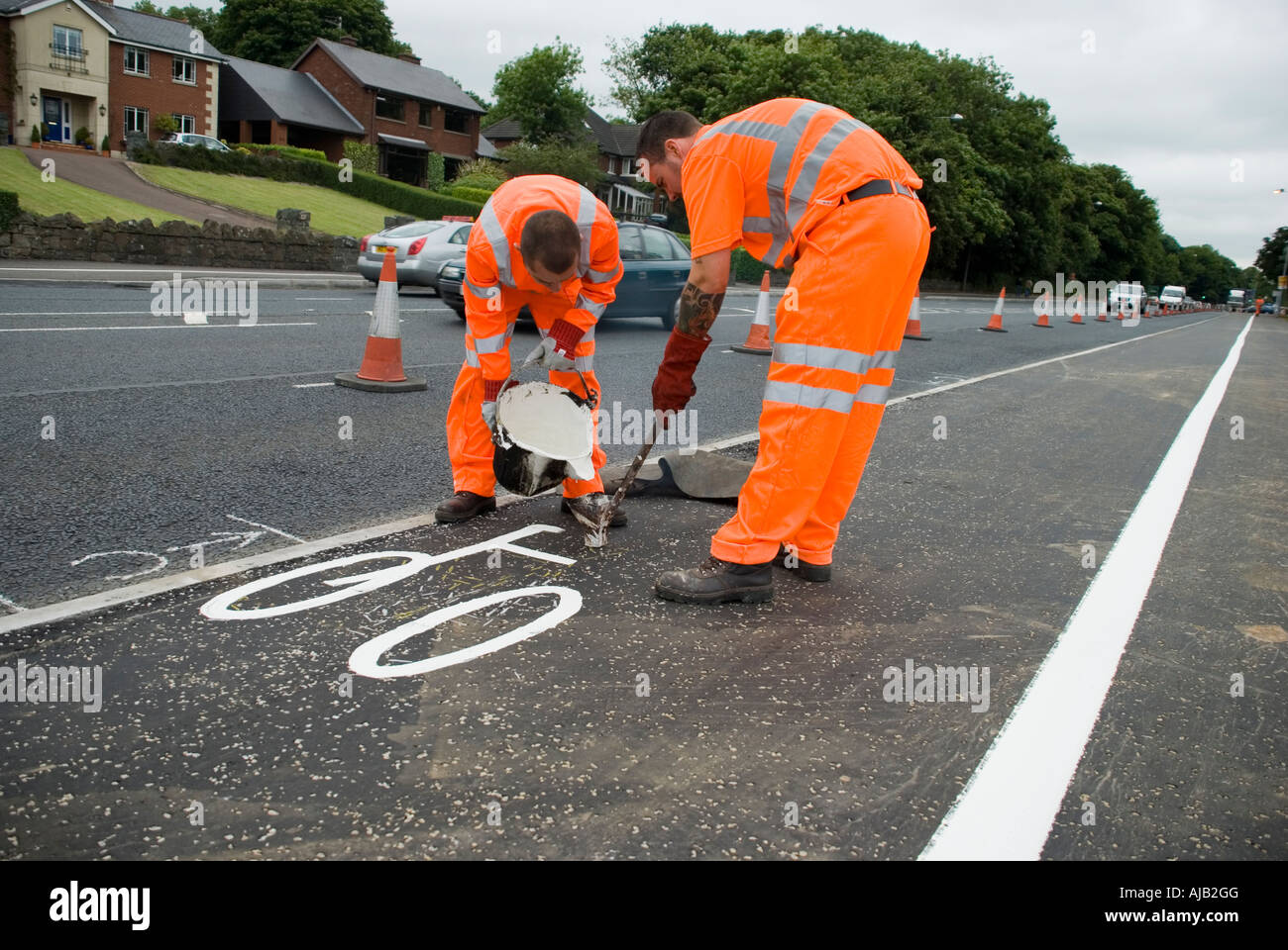 L'homme au travail : les marques routières. Deux hommes en orange hi-vis convient à tracer une voie cyclable avec de la peinture. Banque D'Images