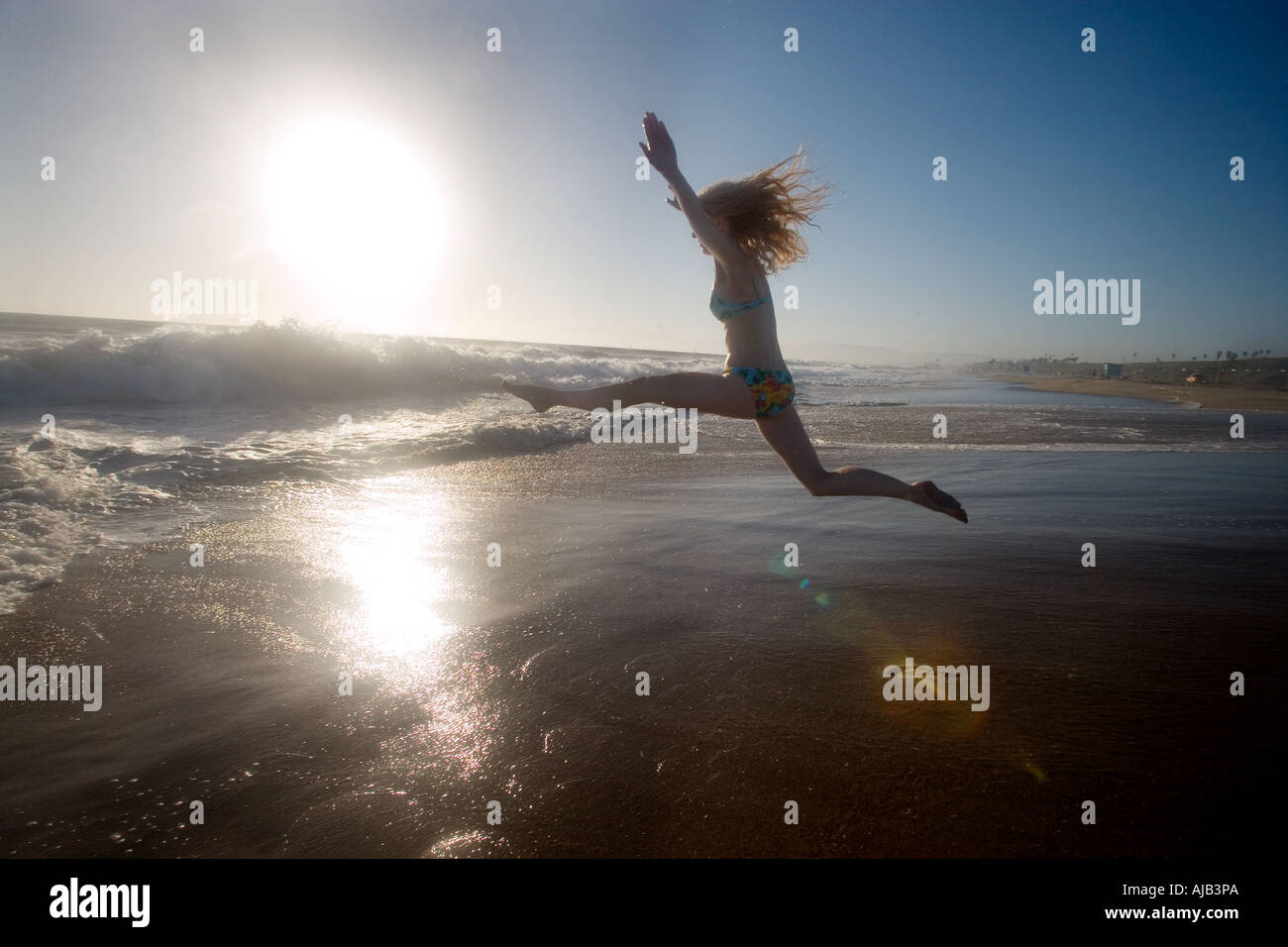 Happy girl saute sur Beach en Californie USA au coucher du soleil Banque D'Images