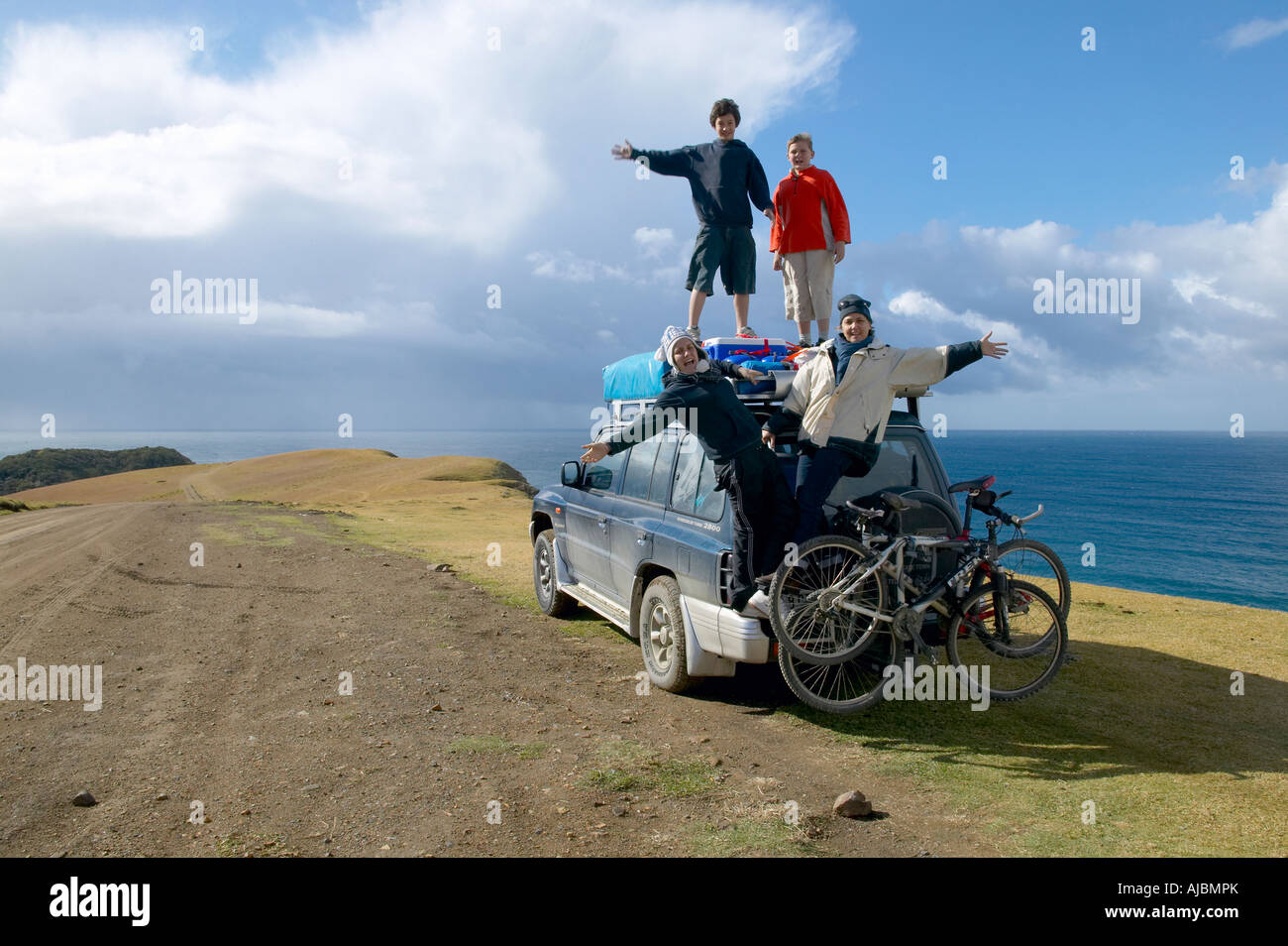Portrait de famille accroché sur un 4x4 avec la mer en arrière-plan Banque D'Images