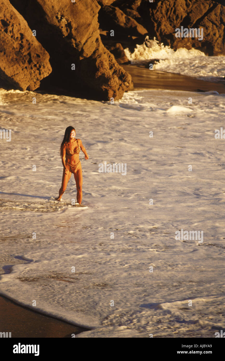 Femme jouant dans les vagues sur la côte de Laguna Beach en Californie, au coucher du soleil Banque D'Images