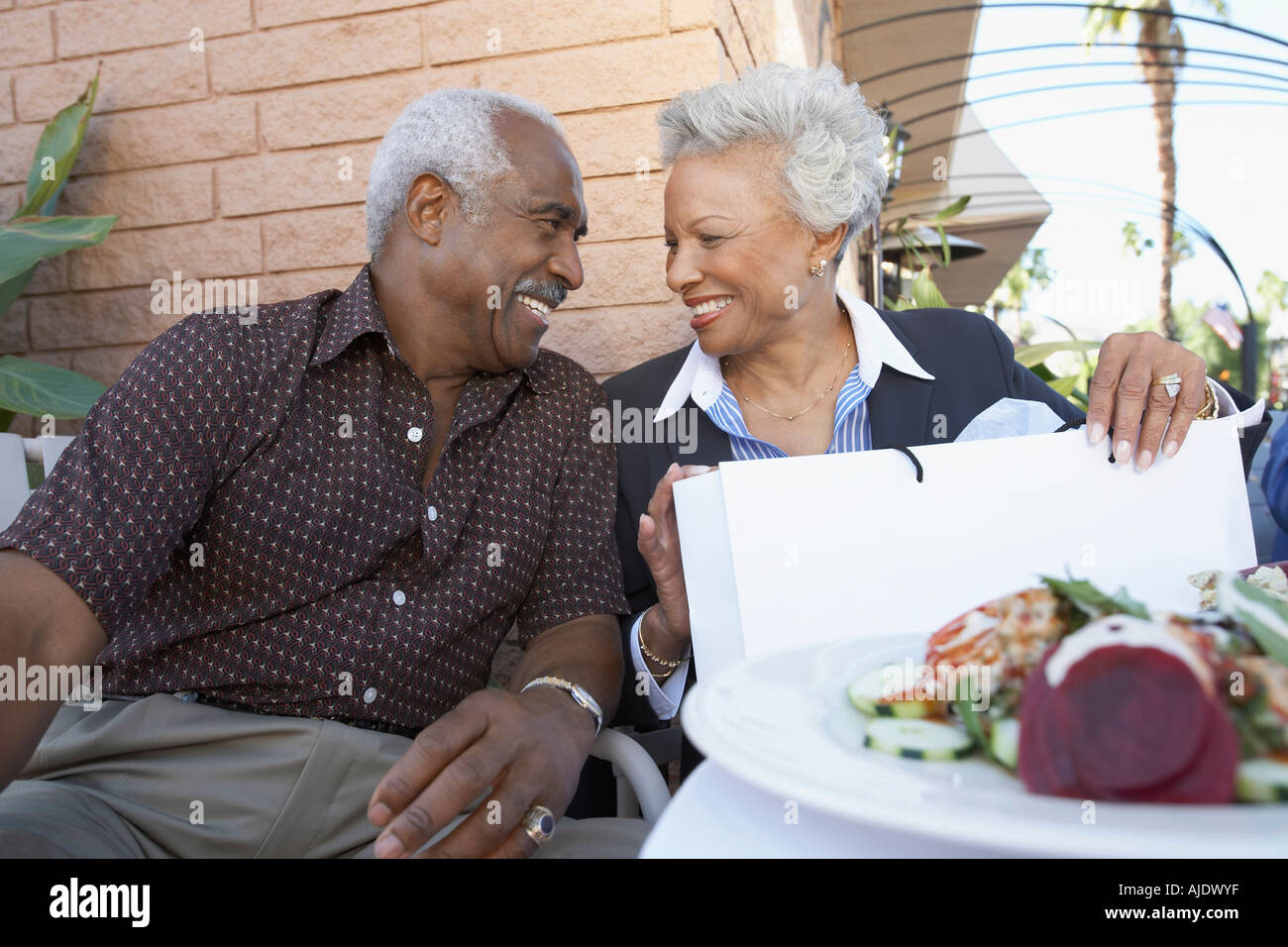Senior Couple sitting outdoors sur voyage de shopping, à la recherche dans les yeux Banque D'Images
