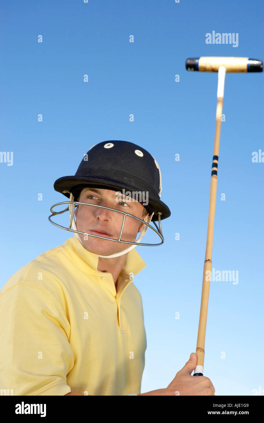 Polo Player port casque avec masque de visage, holding polo stick, side view Banque D'Images