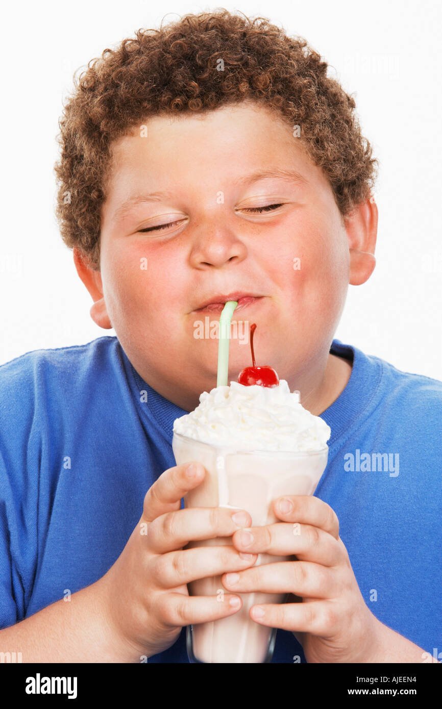 L'excès de boy (13-15) agiter le lait de consommation, les yeux fermés, front view Banque D'Images