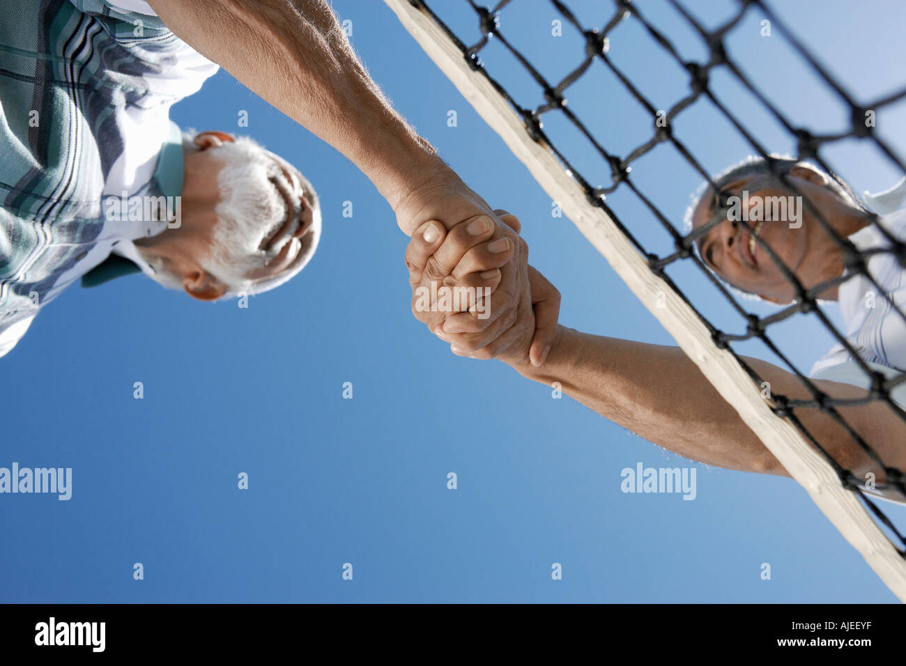 Senior men shaking hands plus net, tennis vue de dessous Banque D'Images