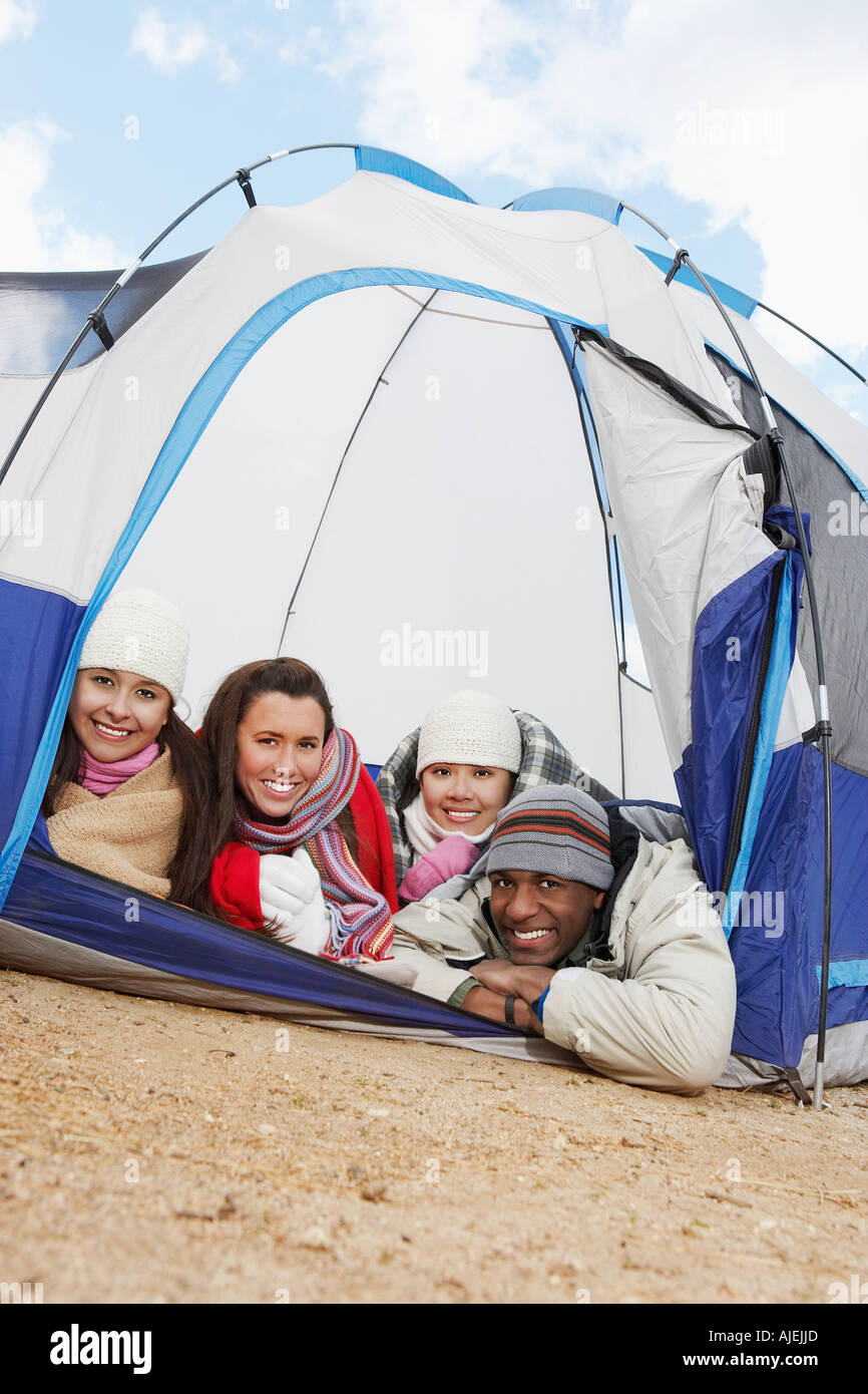 Quatre jeunes adultes se coucher dans petite tente. Banque D'Images