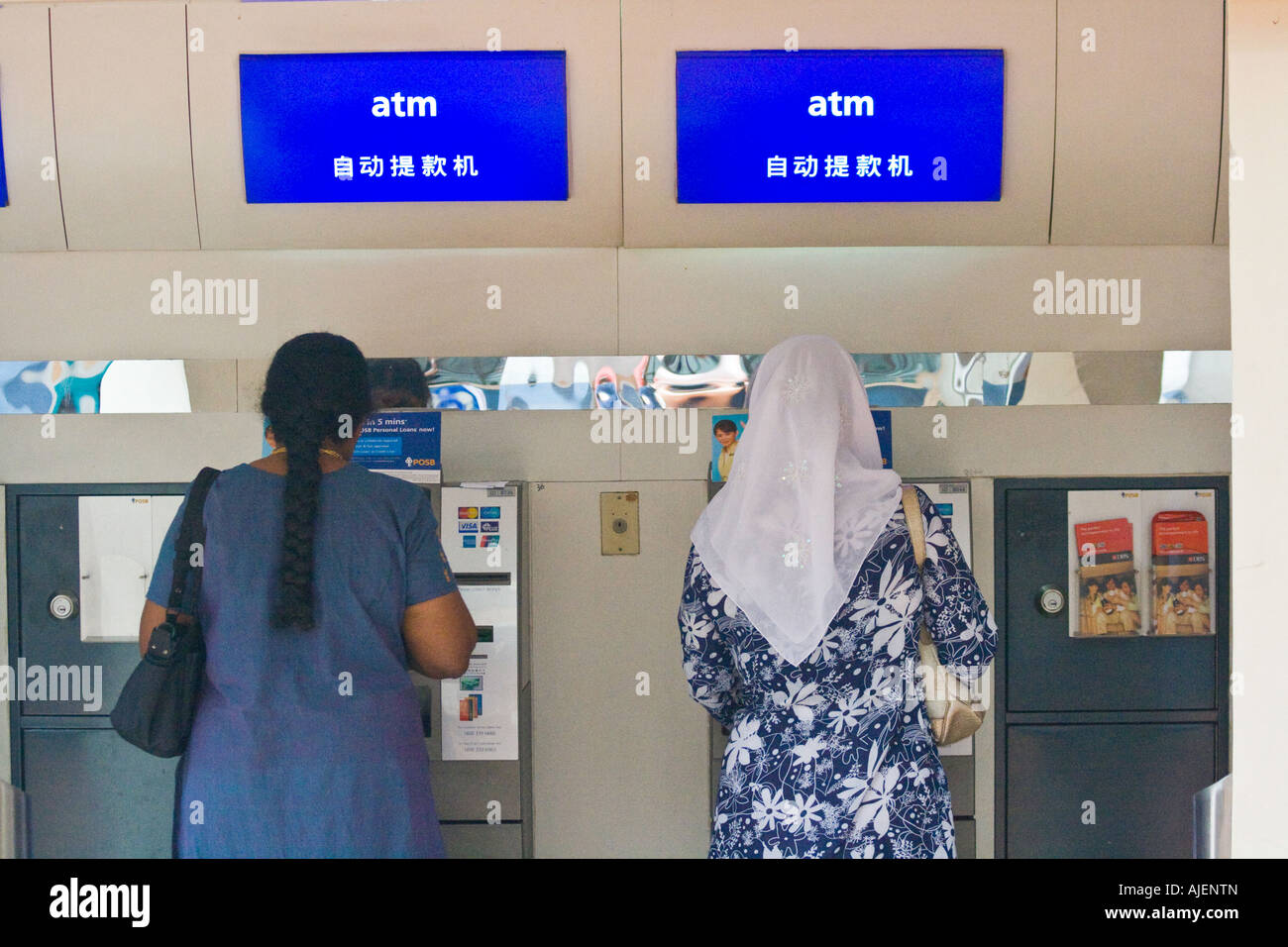 Femme musulmane et hindoue de la dépose de l'argent à un guichet automatique bancaire Banque D'Images