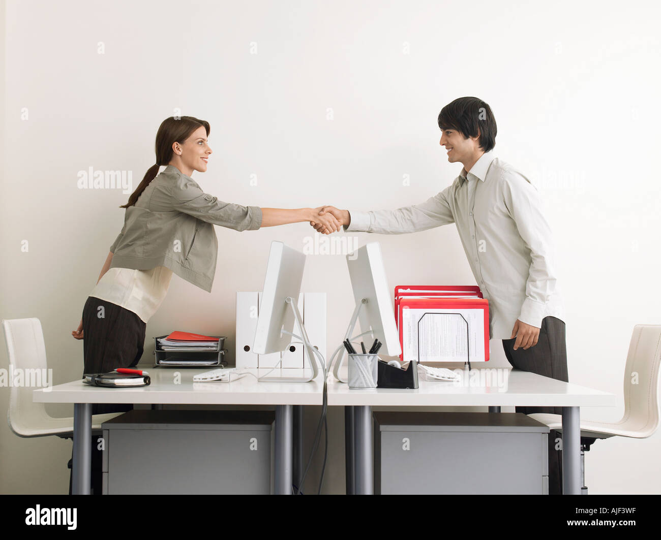 L'homme et la femme se serrer la main au-dessus d'un bureau, vue latérale Banque D'Images