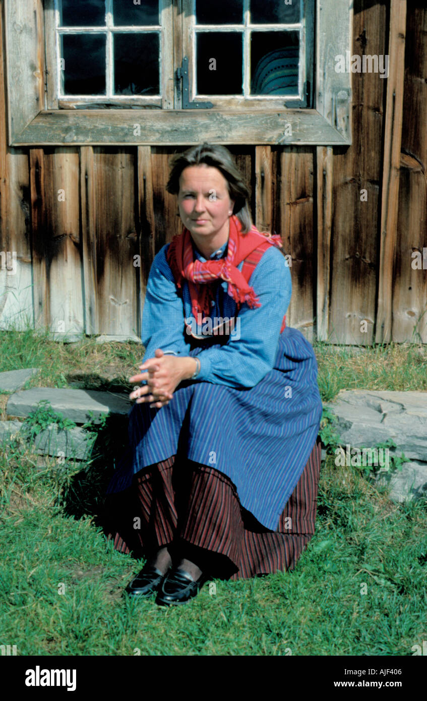 Femme en costume traditionnel assis à l'extérieur d'un bâtiment en bois à un musée de folklore, la Norvège. Banque D'Images Femme en costume traditionnel assis à l'extérieur d'un bâtiment en bois à un musée de folklore, la Norvège. Banque D'Images