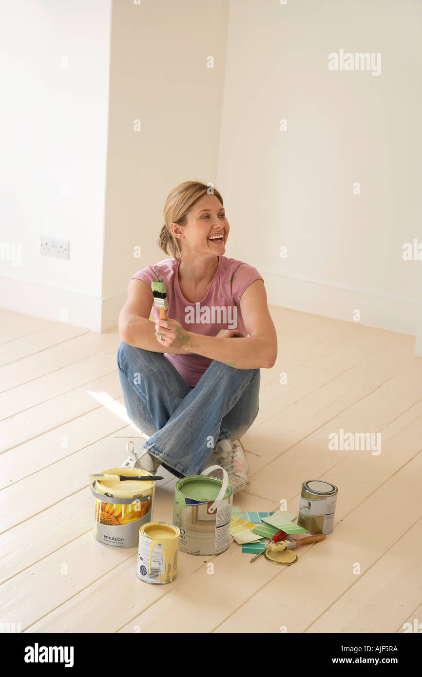 Smiling woman sitting avec matériaux de peinture sur marbre Banque D'Images