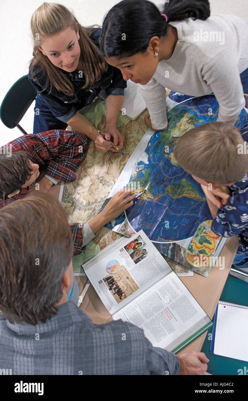 Groupe d'élèves de l'école intermédiaire à l'aide de cartes et d'un globe d'étudier en classe de géographie Banque D'Images
