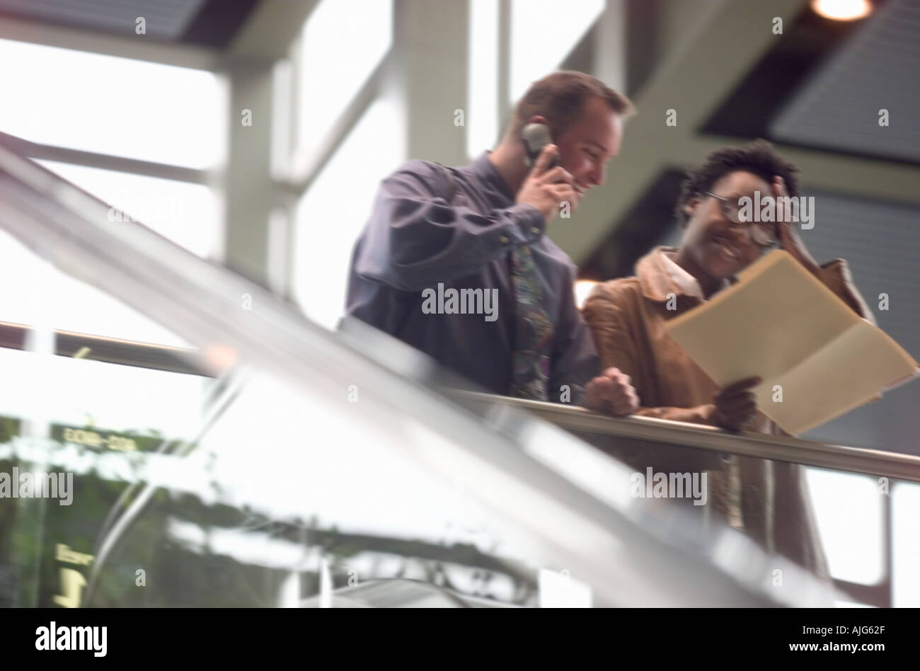 Les hommes et les femmes de la lecture du rapport et using cell phone Banque D'Images