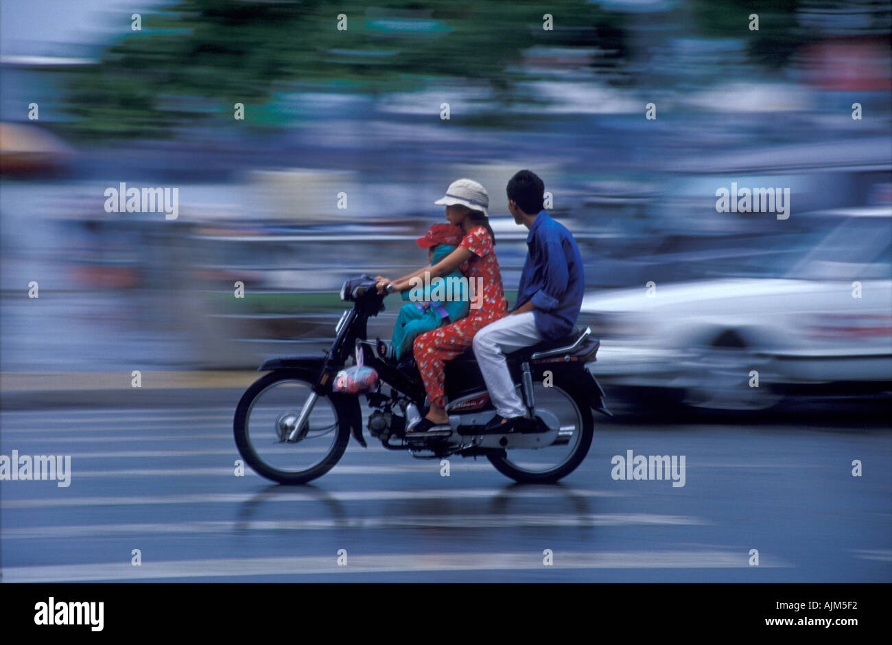 Jeune femme au volant d'une moto en Saigon Vietnam avec enfant devant et  derrière son mari dans une circulation intense dans les ec vietnamiens  Photo Stock - Alamy