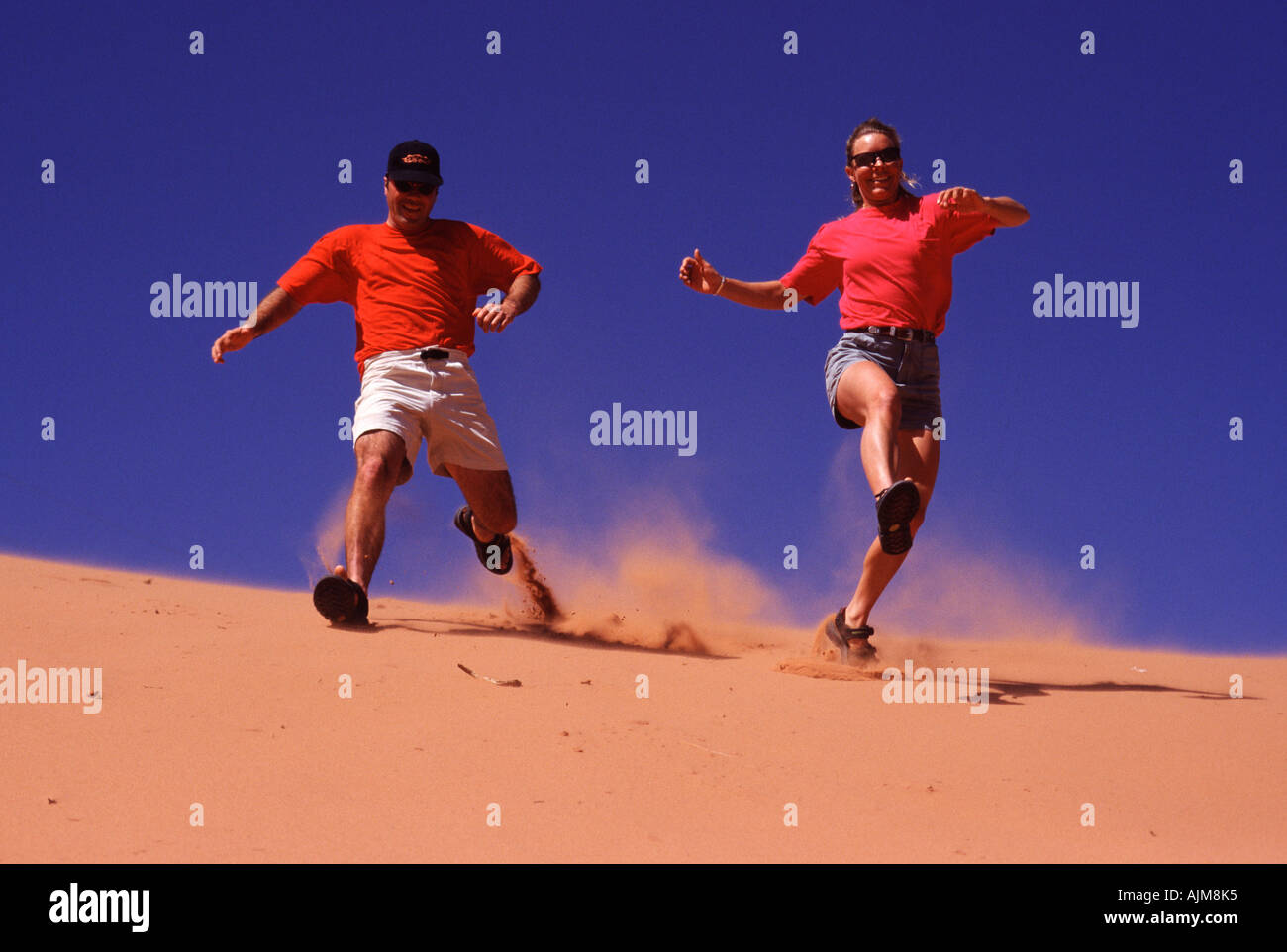 Un homme et une femme sur une dune de sable lors d'une randonnée dans la région de Moab UT Banque D'Images