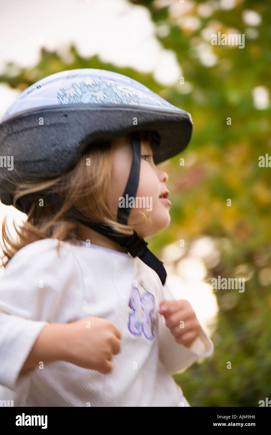 Photo de profil de jeune fille portant un casque de vélo avec des arbres en arrière-plan Banque D'Images