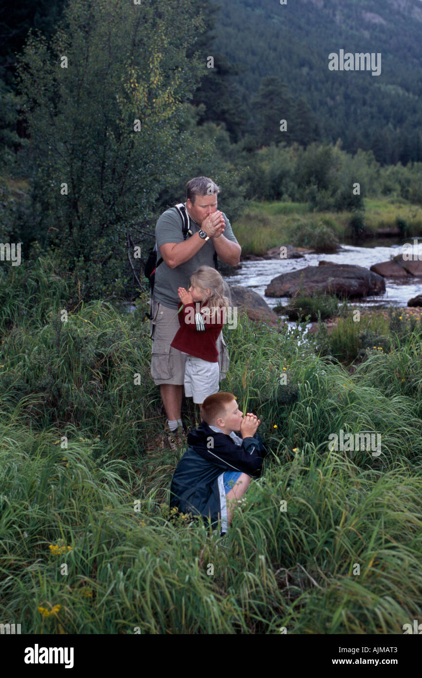 Papa les enfants jouant avec jeu sifflet brins d'herbe du parc Moraine Rocky Mtn l Nat Park CO Banque D'Images