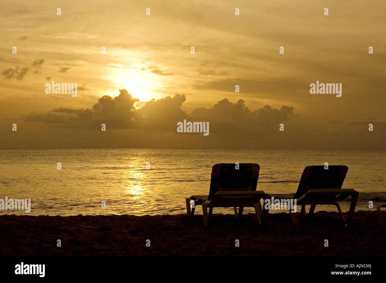 Deux chaises longues sur une plage des Caraïbes vide lors d'un coucher du soleil Banque D'Images