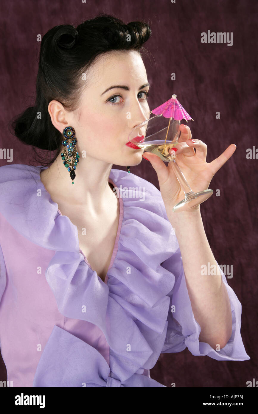 Un Pin Up Girl in a Purple Blouse tenant un verre à cocktail avec un parapluie Rose Banque D'Images