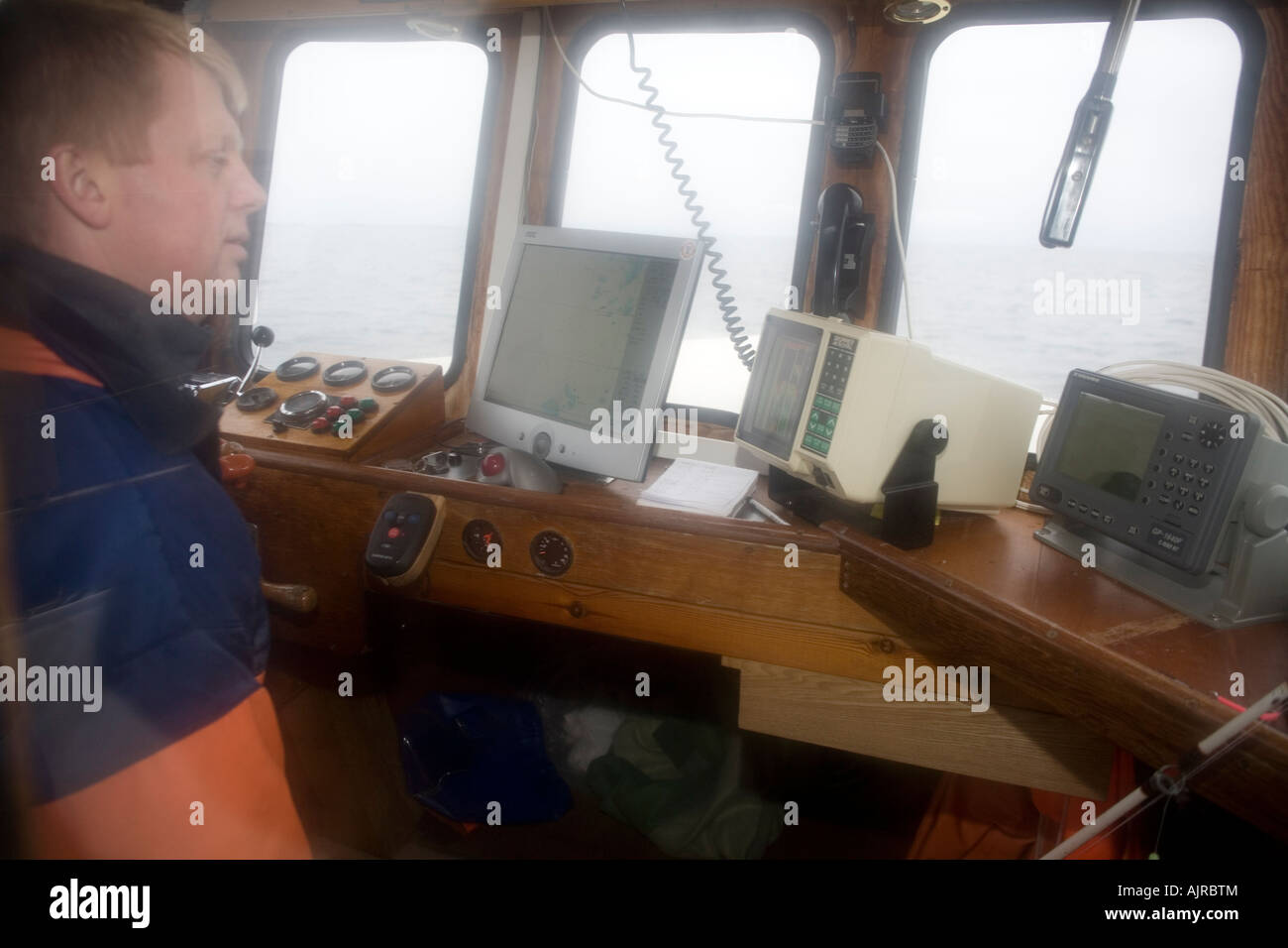 L'homme dans la cabine de son bateau. Les échosondeurs et GPS sont de grandes aides à la navigation dans les eaux côtières peu profondes de l'Europe de l'ouest de la Suède Banque D'Images