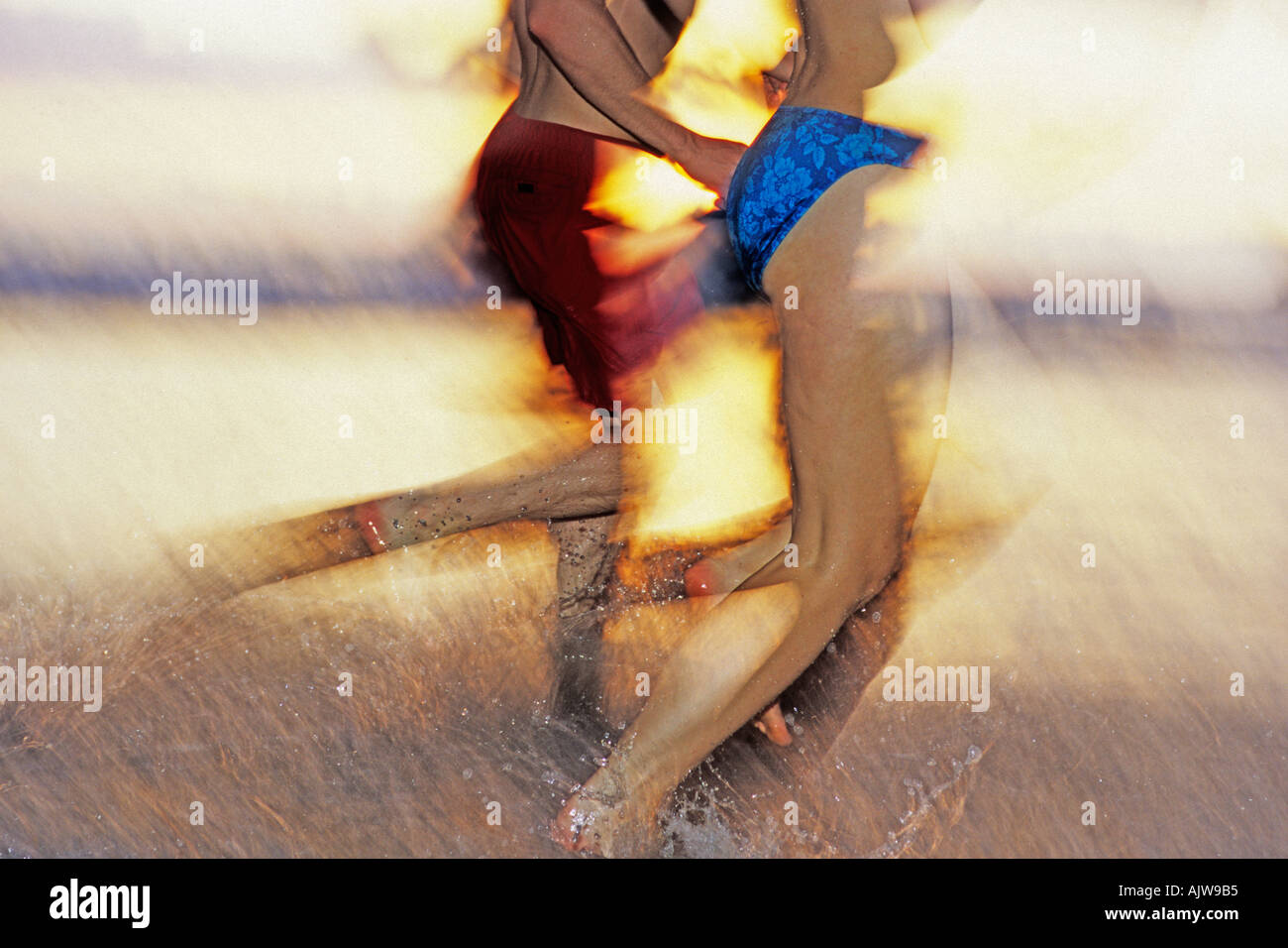 COSTA RICA COUPLE RUNNING ON BEACH AT SUNSET Banque D'Images