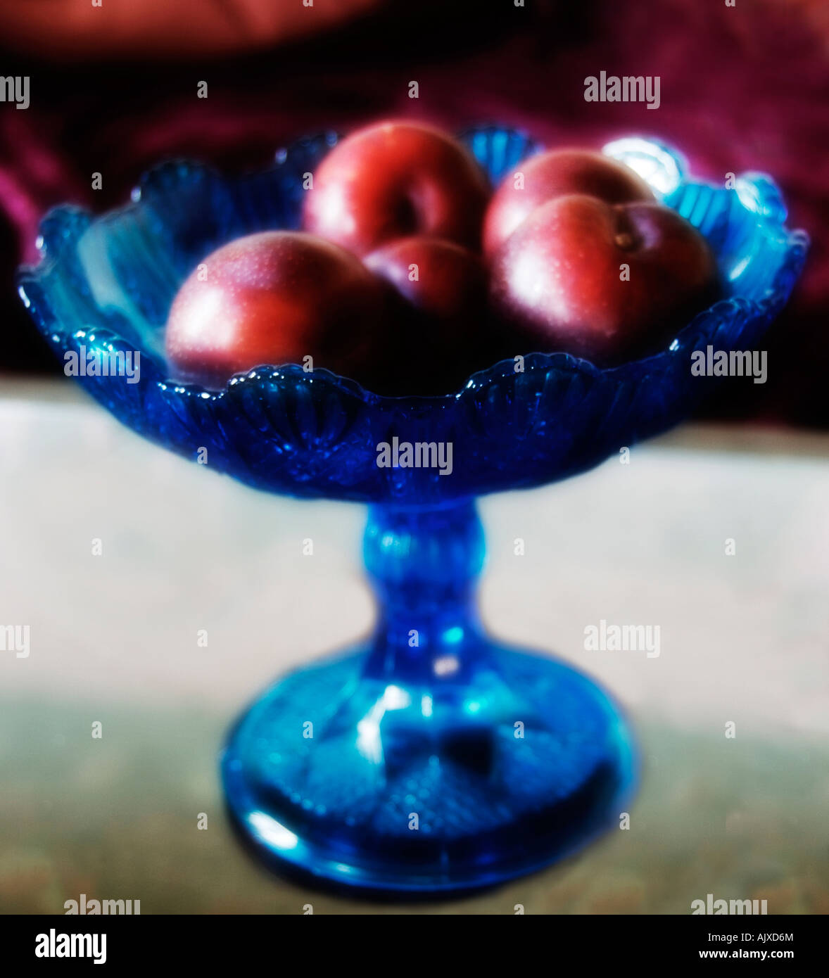 Photo carré bleu d'origine bol de prunes rouges Banque D'Images