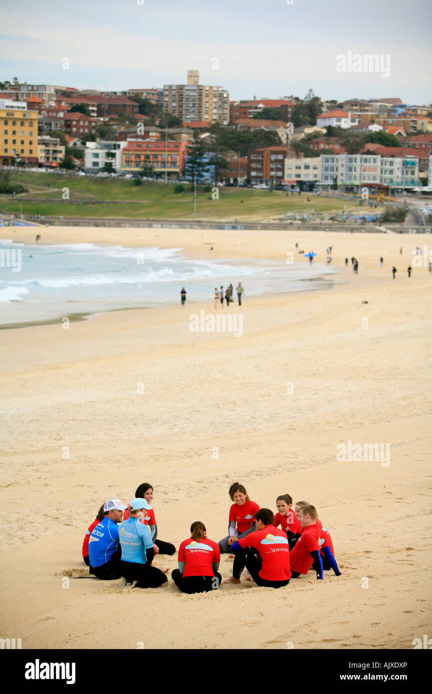 Un groupe de touristes forment un cercle sur la plage de Bondi avant de participer à une école de surf Banque D'Images