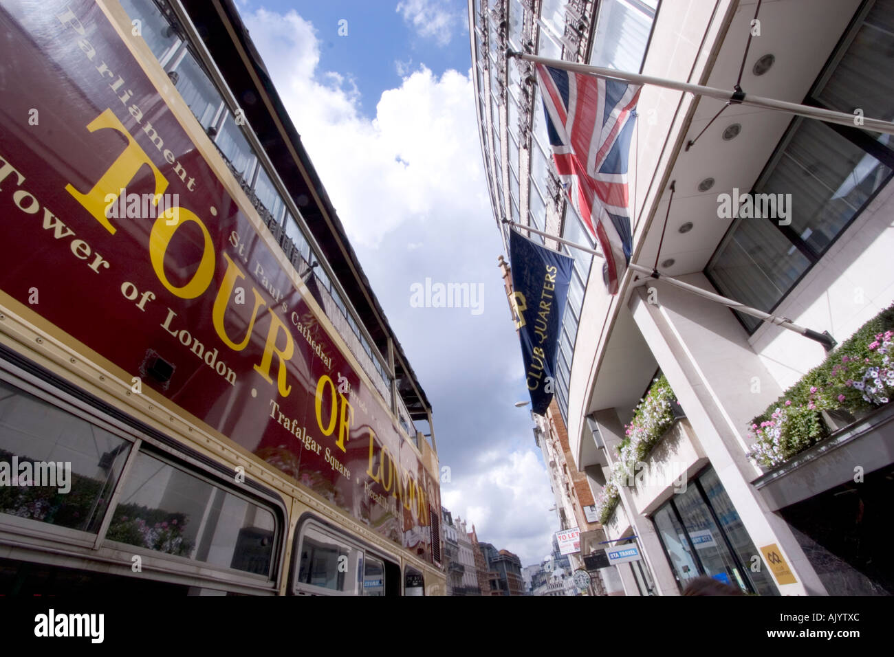 Visite à toit ouvert du bus touristique londonien avec drapeau union Jack flottant sur la façade du magasin Banque D'Images