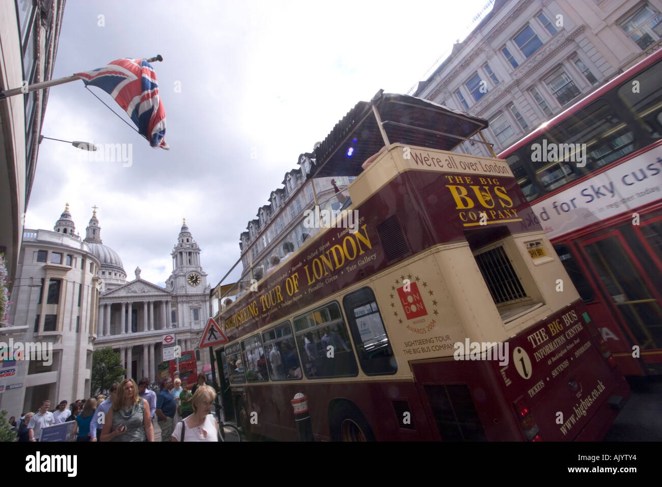Visite à toit ouvert du bus touristique londonien avec drapeau union Jack flottant sur la façade du magasin Banque D'Images