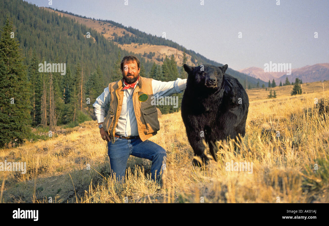 Un homme se tient à côté d'un ours noir dans un pré dans le nord du Nouveau Mexique Banque D'Images