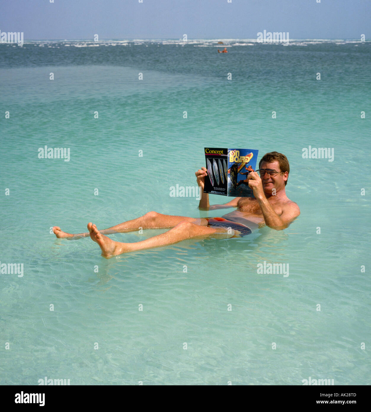 Un homme seul en bref les slips et lunettes flottant et la lecture d'un magazine sur la mer Morte Israël Banque D'Images