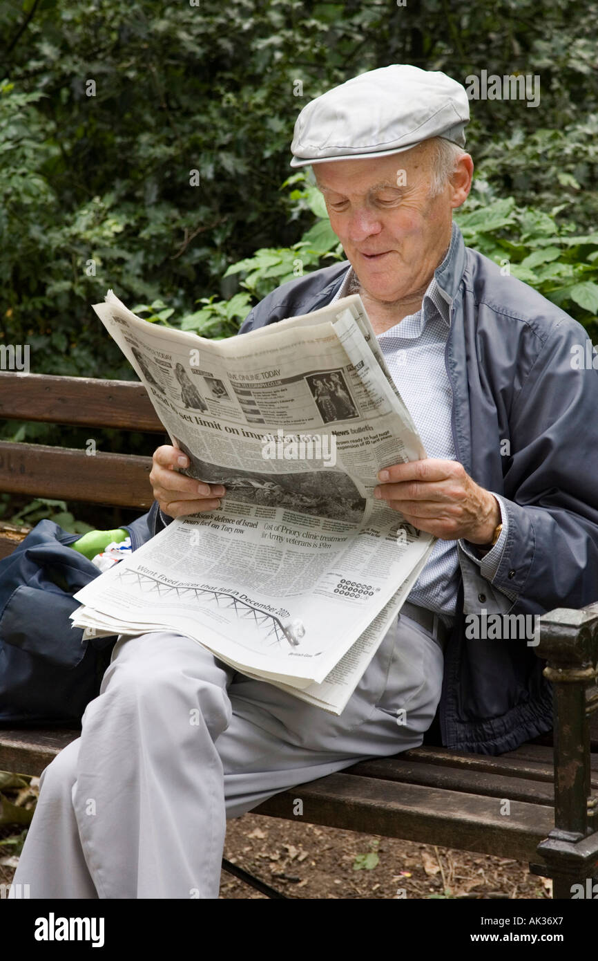 Un vieil homme de lire le journal dans un parc Banque D'Images