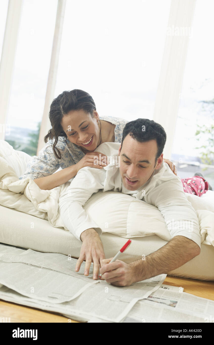 Un couple dans le salon lit tout en lisant le journal Banque D'Images