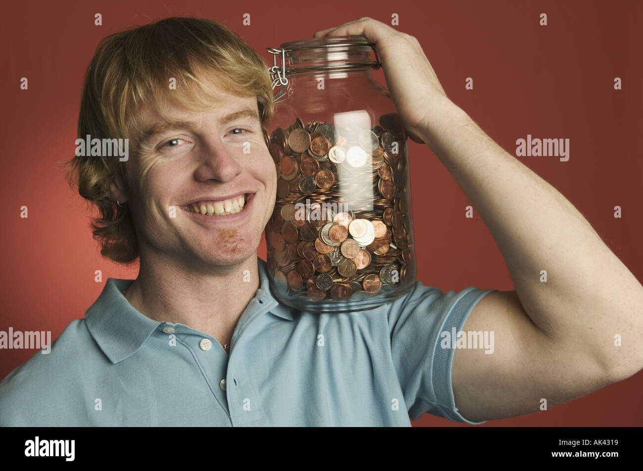 Man smiling tout en tenant un grand verre coin jar Banque D'Images