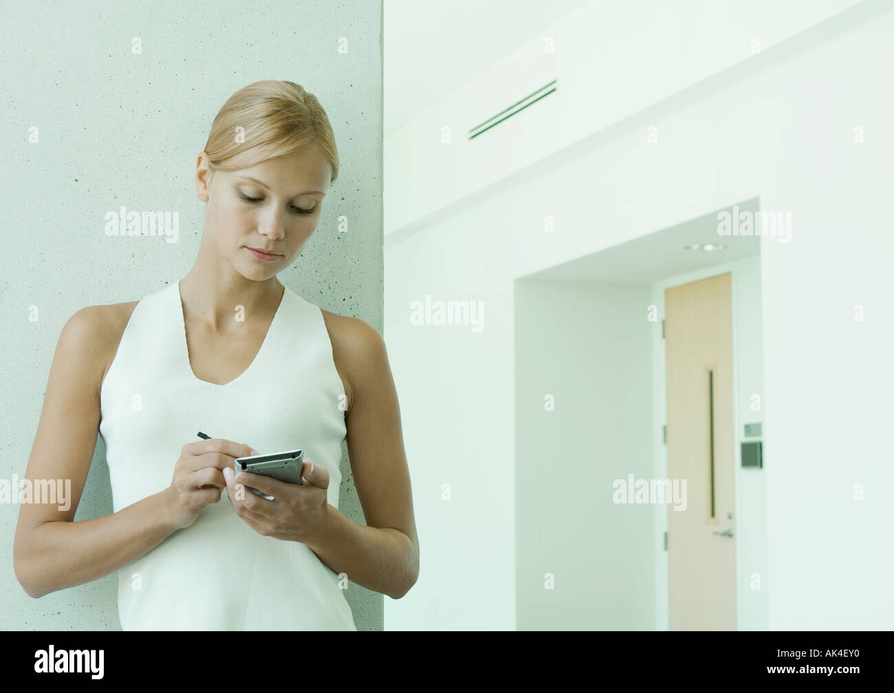 Woman using electronic organizer dans le couloir du bâtiment de bureaux Banque D'Images