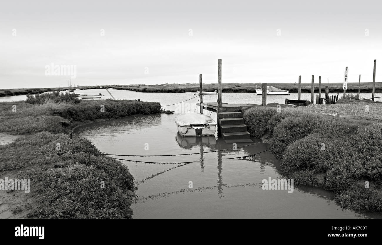 Petit bateau ancré dans la petite baie à marée haute Morston Quay en mono Banque D'Images