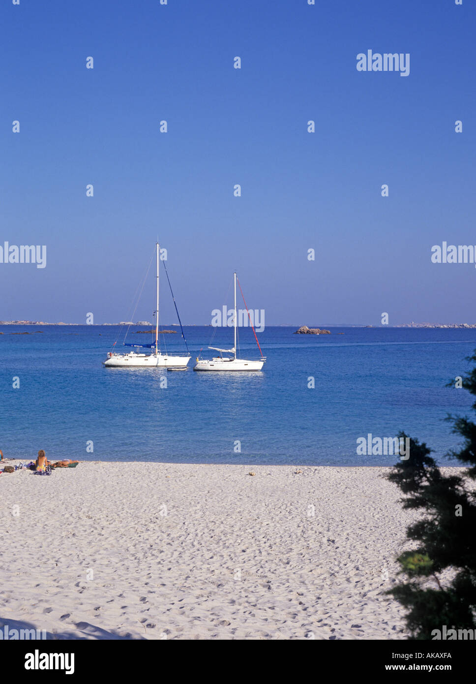 Deux yachts ancrés par beach avec des gens en train de bronzer sur une plage en premier plan Corse Banque D'Images