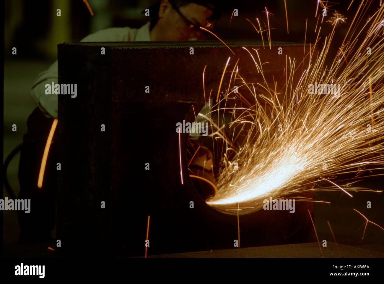 Travailleur d'usine de broyage de Chicago utilise cutter pour lisser et terminer le trou du bloc en acier La production de pluie d'étincelles Banque D'Images