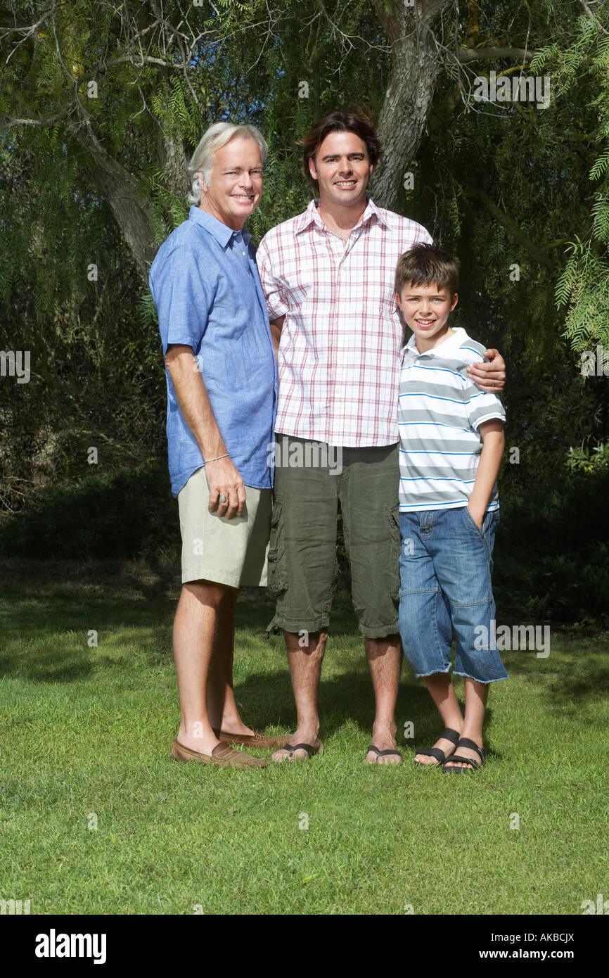 Grand-père, père et fils (10-12) posing under tree Banque D'Images