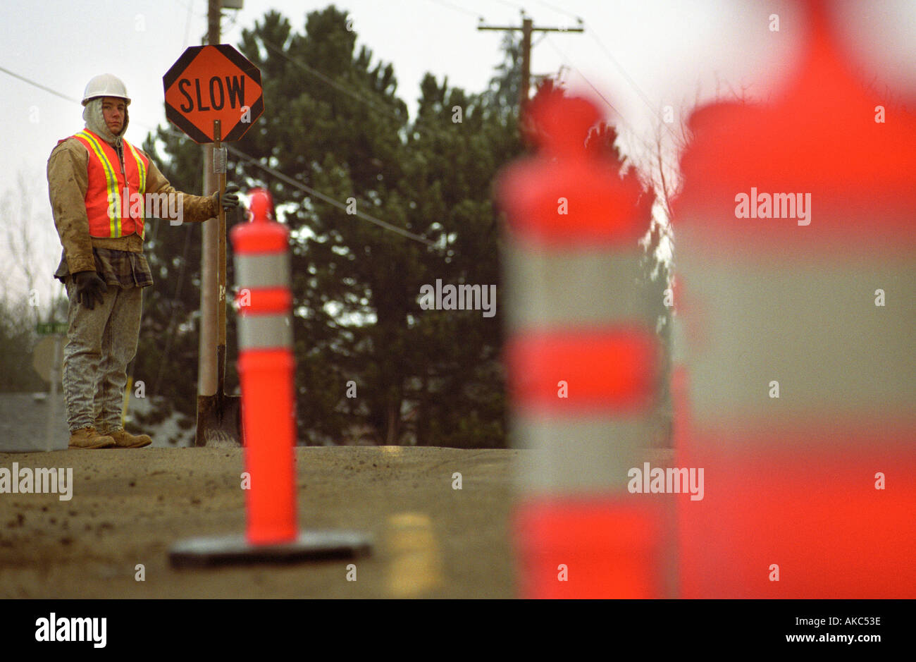 Roadworker lente holding signe avec cônes de construction en premier plan Banque D'Images