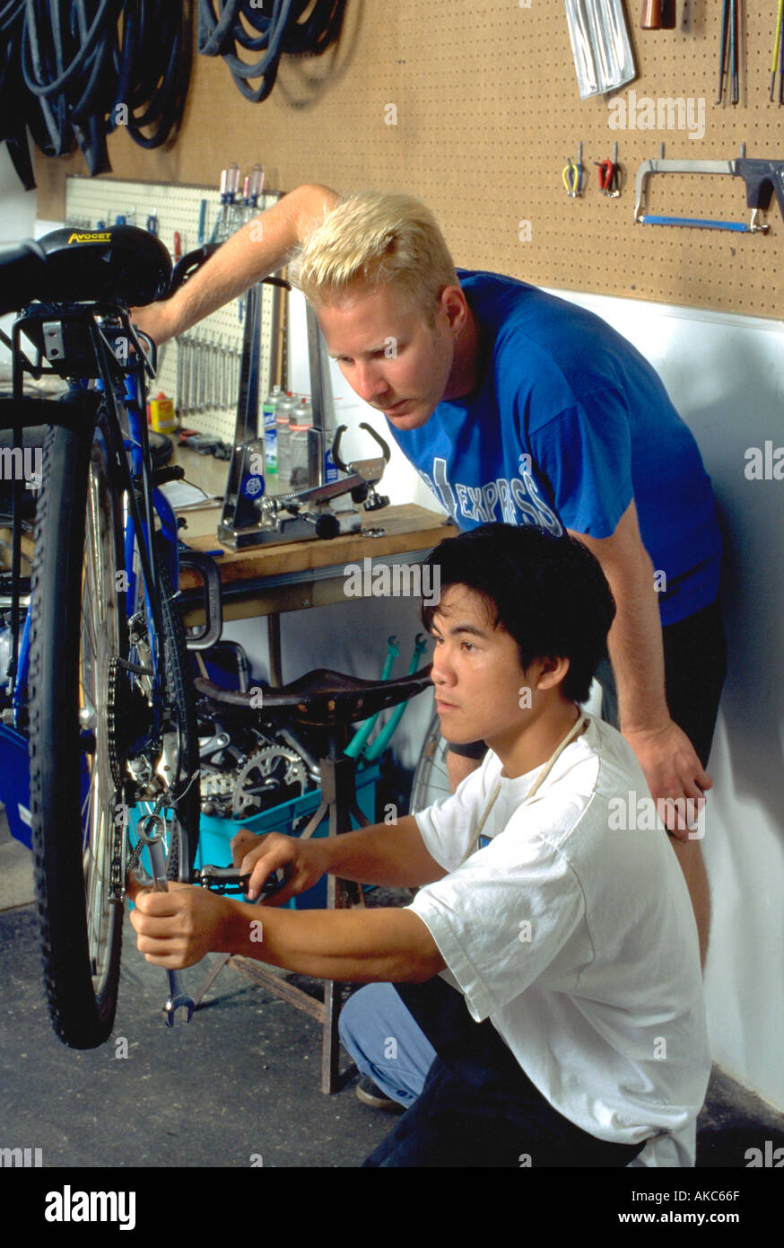 Et des travailleurs âgés de 28 et 15 leader de la réparation vélo au magasin de vélo pour les jeunes. St Paul Minnesota USA Banque D'Images