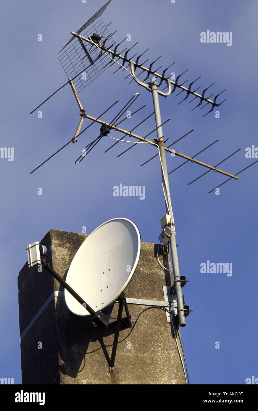Une antenne de télévision analogique et une antenne satellite partager l'espace sur une cheminée Banque D'Images